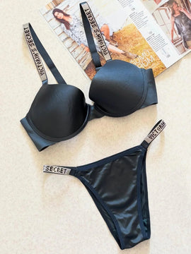 Black Victoria's Secret lingerie set on a textured surface with a magazine in the background.
