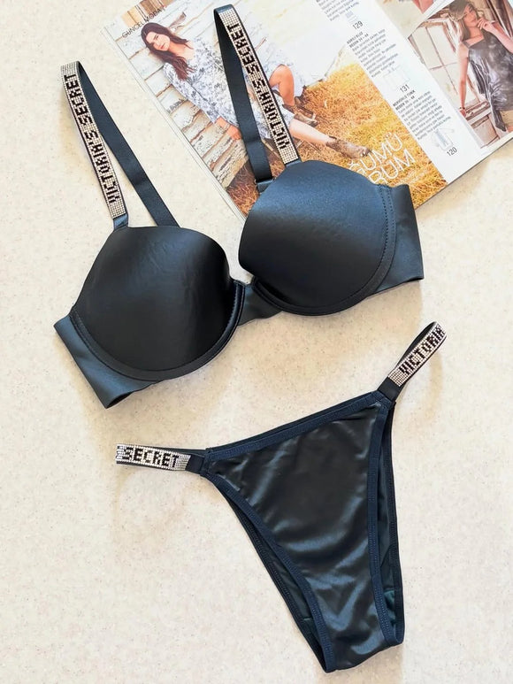 Black Victoria's Secret lingerie set on a textured surface with a magazine in the background.