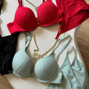 Red and green bras with gold chains on a wooden surface