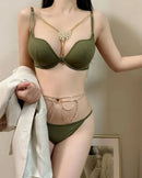Person wearing a green lingerie set with gold accents in a neutral setting