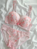 Pink floral lingerie set on a white fabric background
